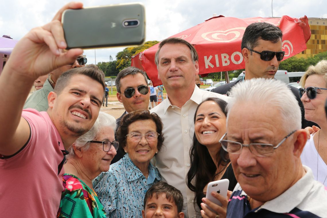 Presidente Jair Bolsonaro posa para foto com turistas na Praça dos Três Poderes em Brasília 
