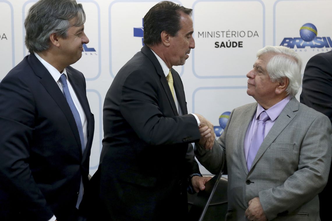 Wilson Dias/Agência Brasil O ministro da Saúde, Gilberto Occhi, cumprimenta o diretor-presidente da Anvisa, William Dib, durante assinatura do primeiro acordo para a redução do teor de açúcar nos alimentos industrializados.