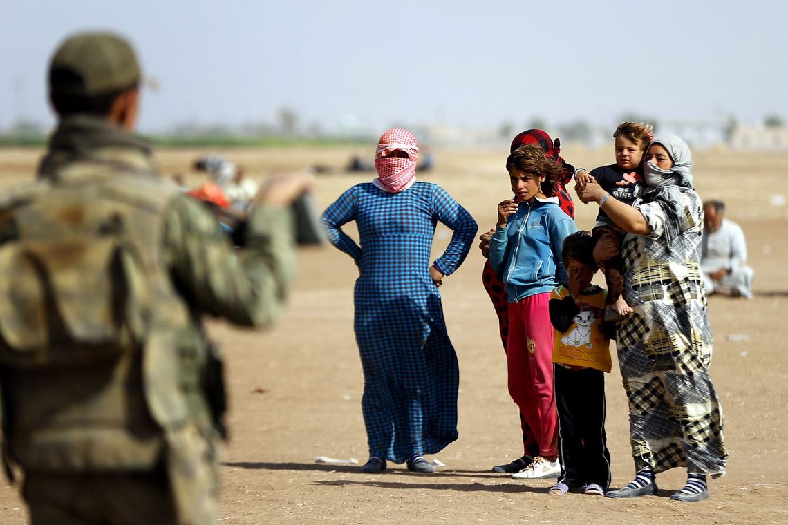 Refugiados sírios aguardam na fronteira com a Turquia para fugir dos ataques do Estado Islâmico (EPA/Sedat Suna/Agência Lusa)