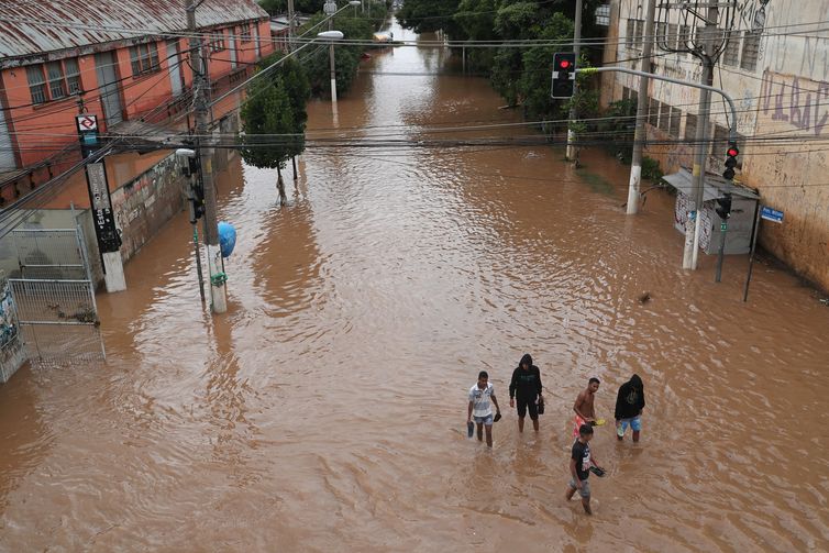 Amanda Perobelli/Reuters/Direitos reservados Pessoas caminham por uma rua inundada após fortes chuvas no bairro de Vila Prudente, em São Paulo.