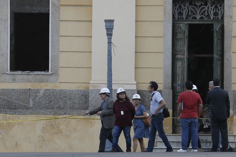 A chefe da missão da Unesco, Cristina Menegazzi (de vestido), e o gestor de projetos de conservação José Luiz Perdessoli Junior (camisa azul clara), chegam ao Museu Nacional do Rio de Janeiro.