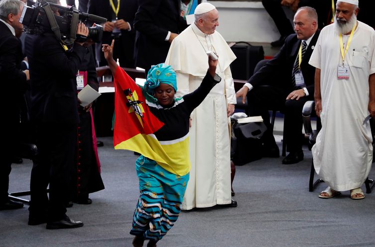 Faithful dances as Pope Francis is seen at the background during an interreligious meeting at Maxaquene Pavilion in Maputo, Mozambique September 5, 2019. REUTERS/Yara Nardi
