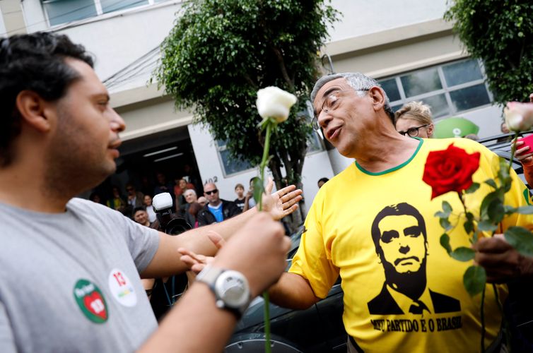 Apoiador (L) do candidato presidencial Fernando Haddad entrega uma rosa a um apoiante de Jair Bolsonaro durante um segundo turno em So Paulo, Brasil 28 de outubro de 2018. REUTERS / Nacho Doce