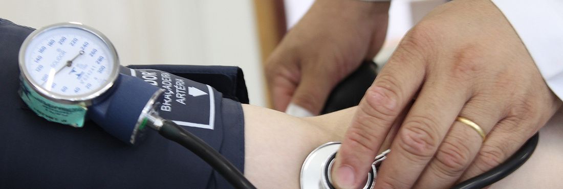 Atendimento Médico Médico aferindo pressão arterial de paciente.