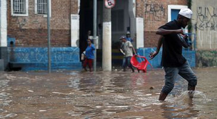 Amanda Perobelli/Reuters/Direitos reservados Pessoas caminham por uma rua inundada após fortes chuvas no bairro de Vila Prudente, em São Paulo.