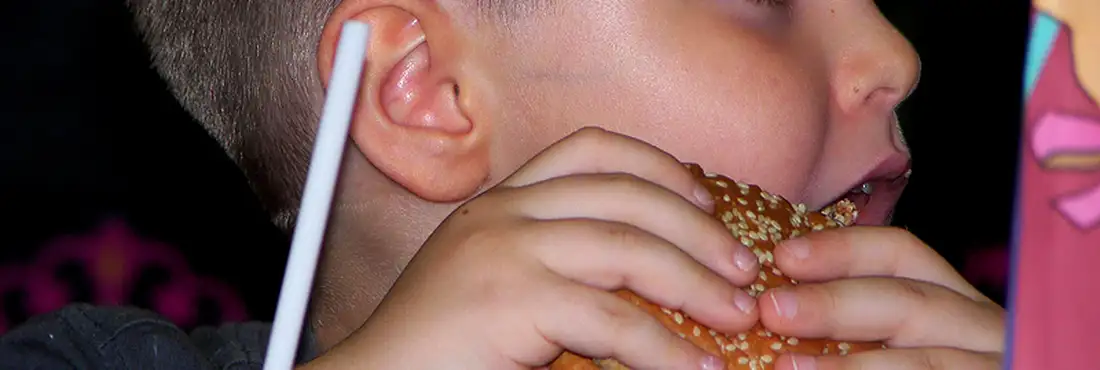 Criança comendo hamburguer Criança comendo hamburguer