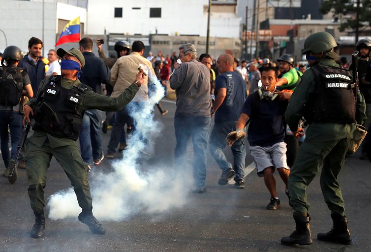 Um militar lança uma bomba de gás lacrimogêneo perto da Base Aérea &quot;La Carlota&quot;, em Caracas, Venezuela.