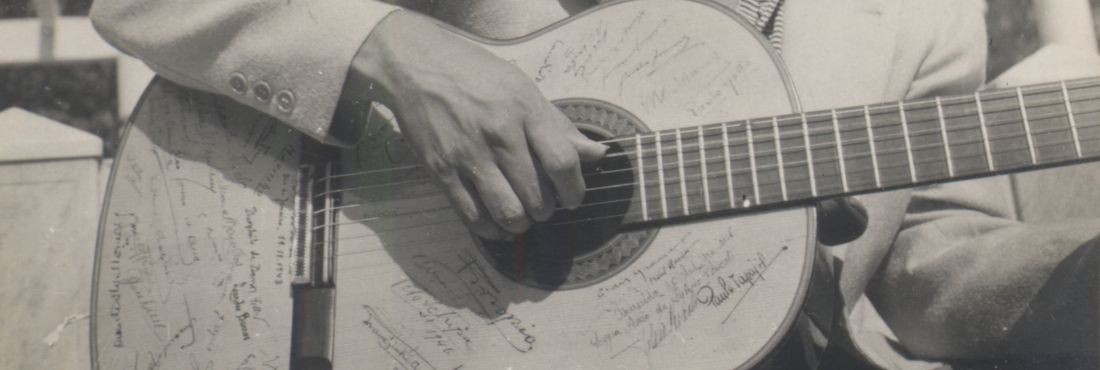 Caymmi com seu violão Dorival sentado, segurando seu violão autografado