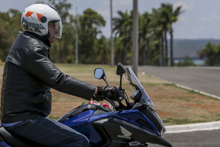 O presidente Jair Bolsonaro chega de moto ao Palácio da Alvorada e cumprimenta turistas
