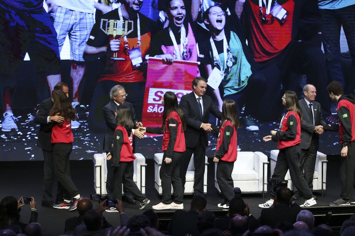 Rovena Rosa/Agência Brasil O presidente da Fiesp, Paulo Skaf, o presidente Jair Bolsonaro e os ministros da Economia, Paulo Guedes, e da Defesa, general Fernando Azevedo e Silva, cumprimentam a equipe de robótica do Sesi Birigui, campeã mundial no Uruguai.