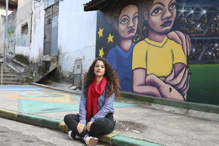 A artista Afolego em frente ao mural pintado por ela, Sarah Lorenk e Clara Leff para a Copa do Mundo Feminina, em Brasilândia, zona norte.