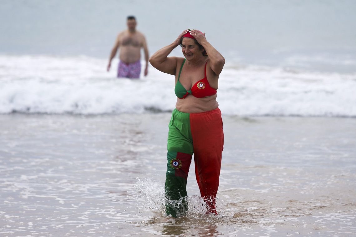 MIGUEL A.LOPES/Lusa Lisboa - Mulher vestida com as cores da bandeira portuguesa participam da tradição de tomar um banho de mar durante as celebrações do Ano-Novo (MIGUEL A.LOPES/Lusa)