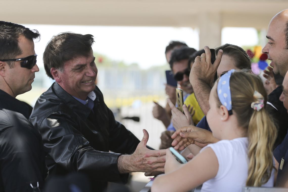 O presidente Jair Bolsonaro chega de moto ao Palácio da Alvorada e cumprimenta turistas