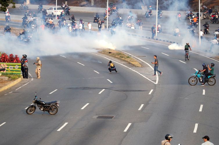 Partidários da oposição venezuelana reagem ao gás lacrimogêneo perto da Base Aérea &quot;La Carlota&quot;, em Caracas, Venezuela.
