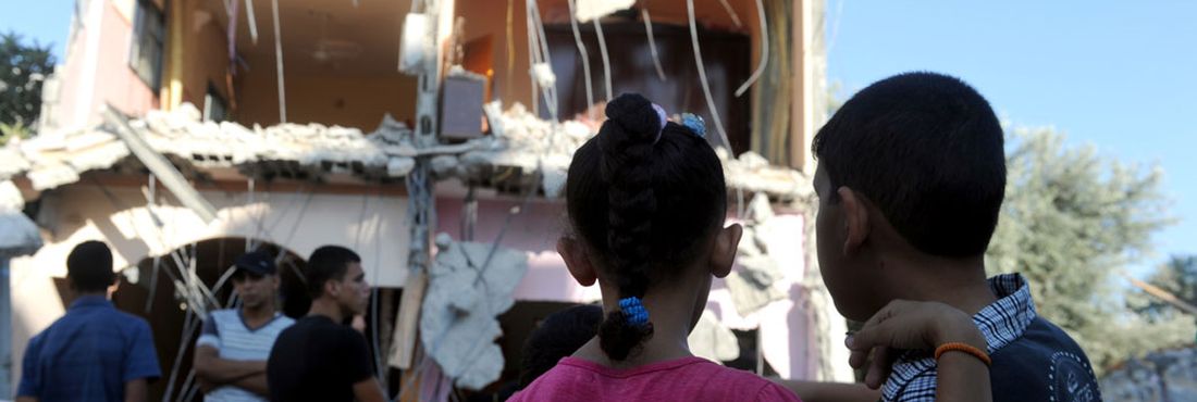 Ataque de Israel destrói habitação em campo de refugiados, em Gaza Dois garotos observam uma casa que foi destruída por um ataque israelense no campo de refugiadaos Maghazi, em Gaza