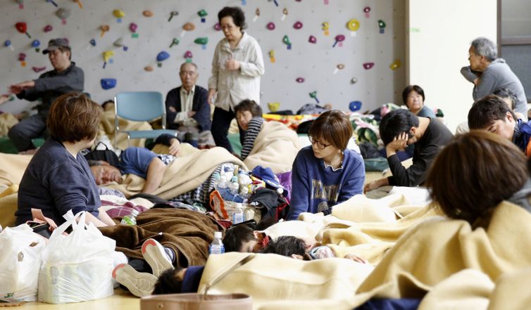 Moradores que foram retirados de suas casas depois de um terremoto, abrigados em um ginásio que funciona como um centro de evacuação improvisado, em Murakami, província de Niigata, Japão.