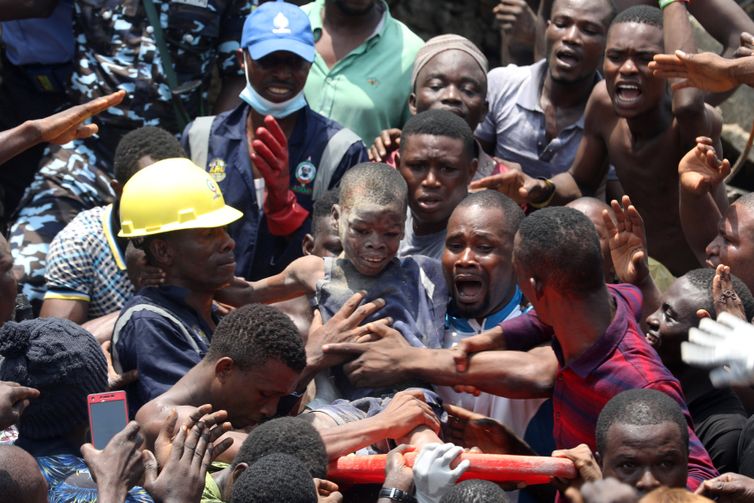 Temilade Adelaja/Reuters/Direitos Reservados Men carry a boy who was rescued at the site of a collapsed building containing a school in Nigeria's commercial capital of Lagos, Nigeria March 13, 2019. REUTERS/Temilade Adelaja