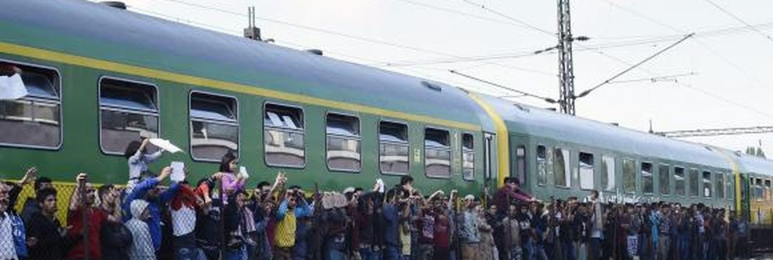 Migrantes e policiais durante distribuição de alimentos na Estação Ferroviária de Bicske, na Hungria