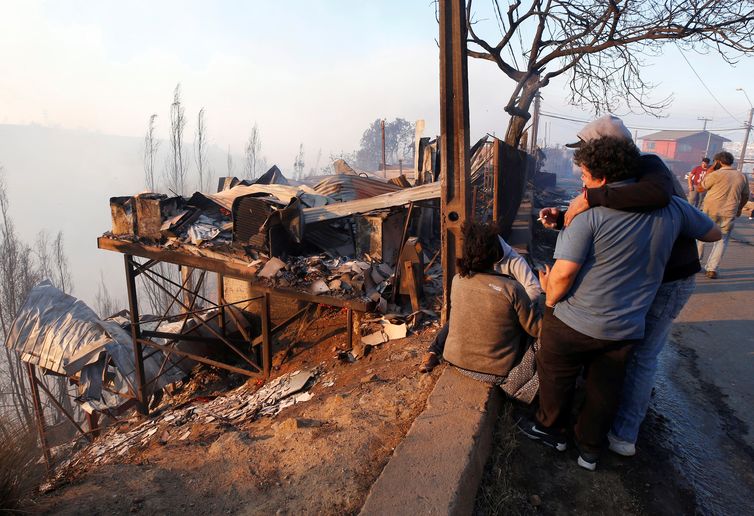 People react next to the debris of their house following the spread of wildfires in Valparaiso, Chile, December 24, 2019. REUTERS/Rodrigo Garrido