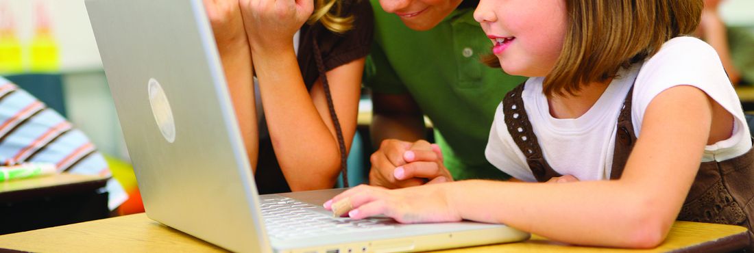 Crianças usando computador em sala de aula
