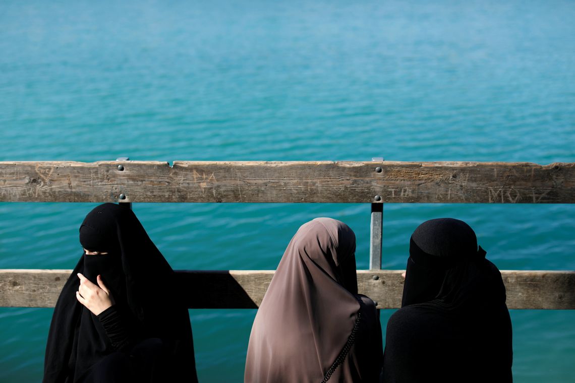Alaa (L), 21, Amina (C), 24, and Nayab, 18, sit on a dock during a visit to Karlstrup Kalkgrav, a lake near Karlstrup located outside Copenhagen, Denmark, July 19, 2018. REUTERS/Andrew Kelly SEARCH "DENMARK VEIL" FOR THIS STORY. SEARCH
