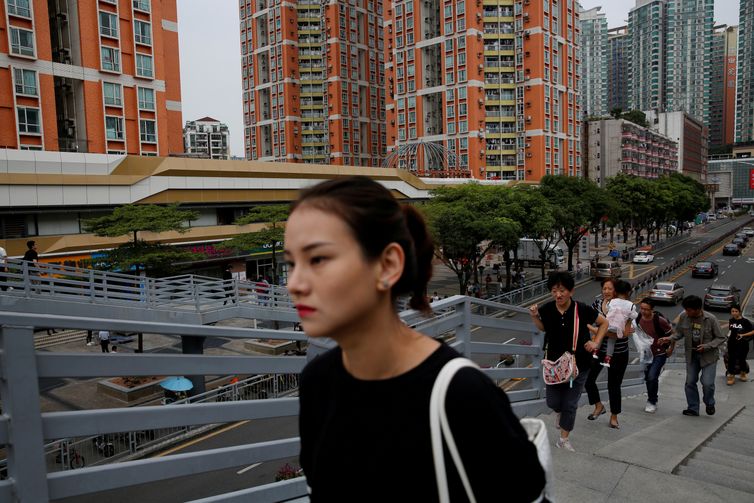 FILE PHOTO: People walk past newly built residential flats in Shenzhen, Guangdong Province, China October 26, 2019. REUTERS/Tyrone Siu/File Photo