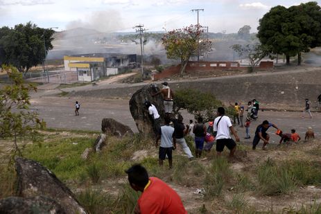 Pessoas se escondem atrÃ¡s de uma rocha durante confrontos na fronteira venezuelana, em Pacaraima, Brasil 24 de fevereiro de 2019. REUTERS / Ricardo Moraes
