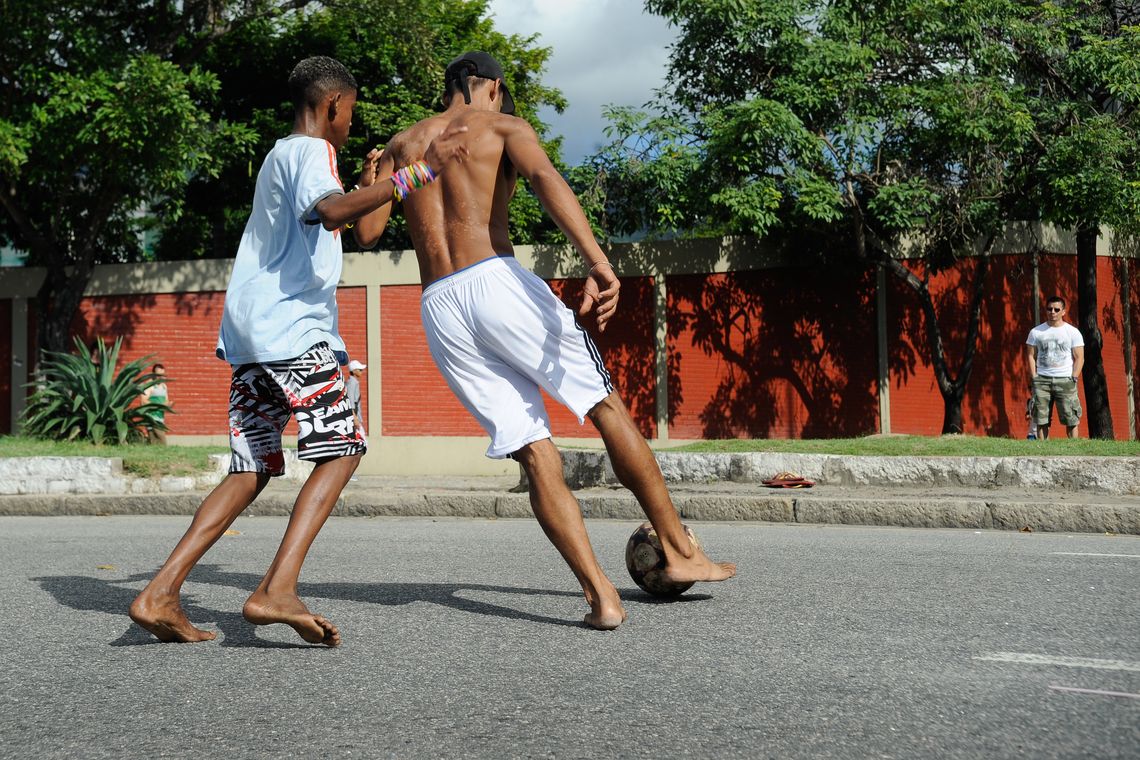 Tânia Rêgo/Agência Brasil Meninos da comunidade Metrô-Mangueira jogam futebol e interagem com turistas em rua interditada por policiais nos arredores do estádio do Maracanã (Tânia Rêgo/Agência Brasil)