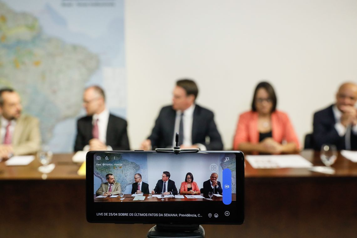 Isac Nóbrega/PR O presidente Jair Bolsonaro faz transmissão ao vivo ao lado do ministro da Educação, Abraham Weintraub, do advogado-geral da União, André Mendonça, da intérprete de libras, Elizângela, e do líder do governo na Câmara, Major Vitor Hugo.