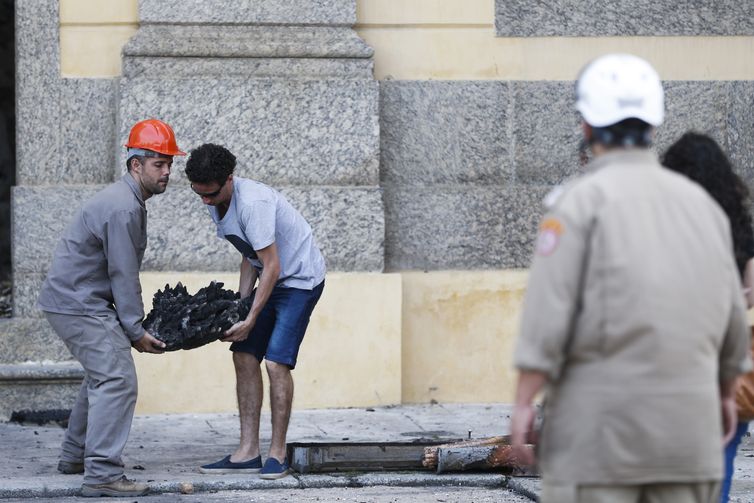 Pesquisadores e funcionários retiram peças dos escombros do Museu Nacional após incêndio.