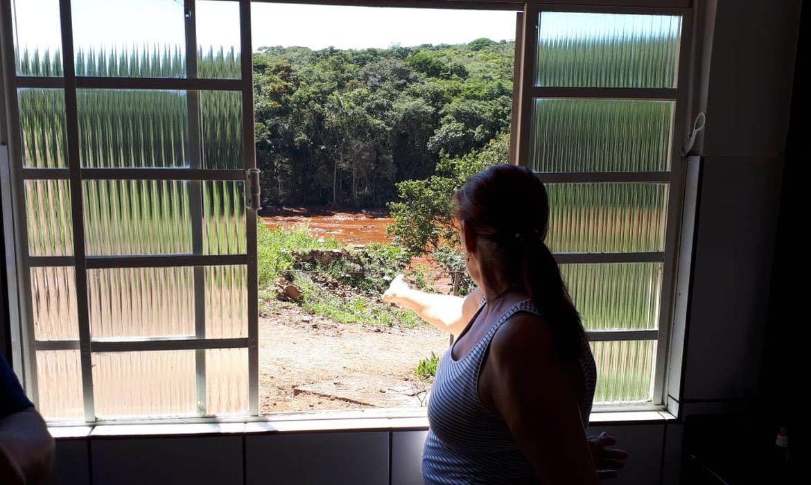 Sandra Maria observa o local tomado pela lama da janela de sua casa em Brumadinho 