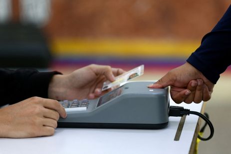 A woman is checked with a fingerprint identity registration device at a polling station in the Liceo Andres Bello during Venezuela's presidential election, in Caracas, Venezuela, July 28, 2024. REUTERS/Fausto Torrealba