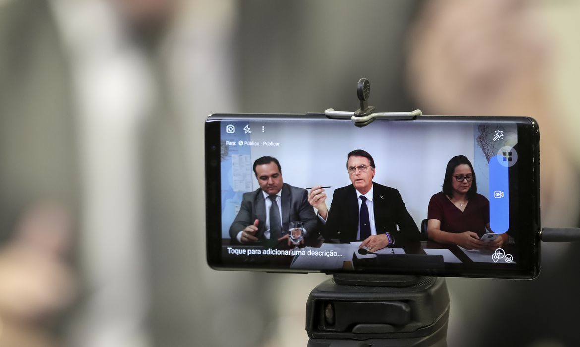 O presidente Jair Bolsonaro faz transmissão ao vivo ao lado do ministro da Secretaria-Geral da Presidência, Jorge Francisco, e da intérprete de libras, Elizângela Castelo Branco.