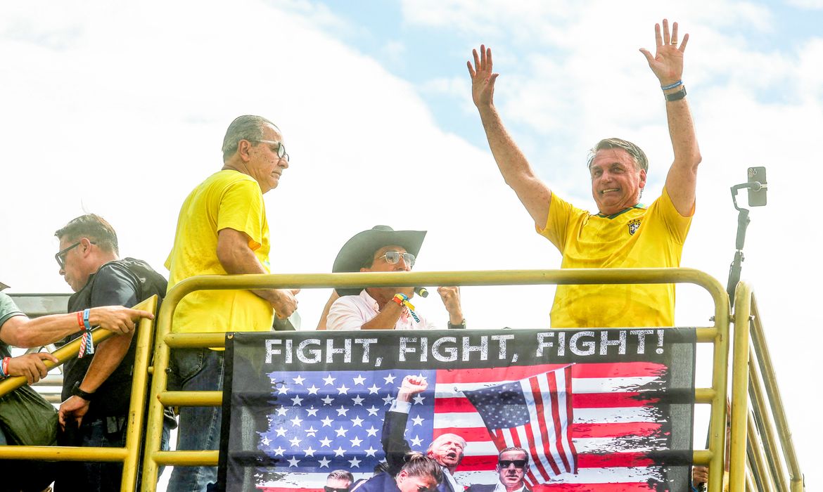 Former Brazilian President Jair Bolsonaro gestures above a banner with an image of U.S. President Donald Trump, as demonstrators gather to support him at Copacabana beach, in Rio de Janeiro, Brazil, March 16, 2025. REUTERS/Pilar Olivares