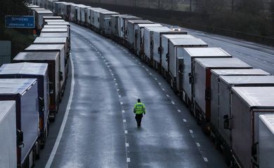 Um homem passa por caminhões estacionados na rodovia M20 perto de Ashford