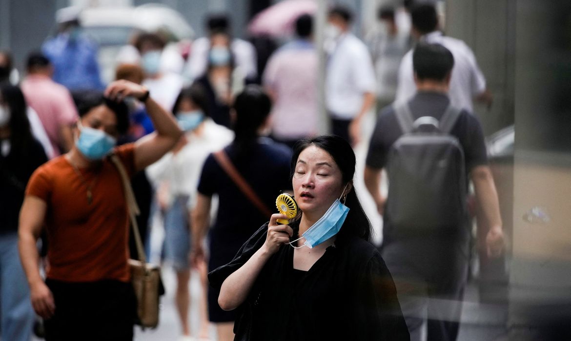 Mulher usa pequeno ventilador portátil enquanto caminha em Xangai, na China