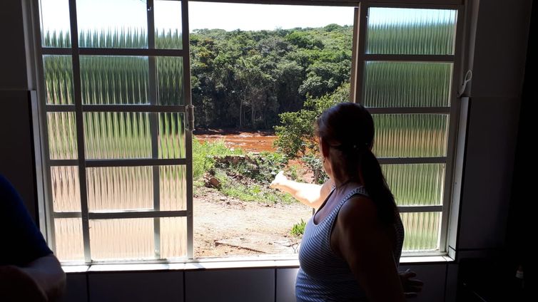 Sandra Maria observa o local tomado pela lama da janela de sua casa em Brumadinho 