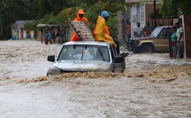 Um grupo de pessoas tenta cruzar uma via alagada in Leogane, no Haiti, após a passagem do Furacão Matthew. O país já registrou 21 mortes em decorrência do furacão