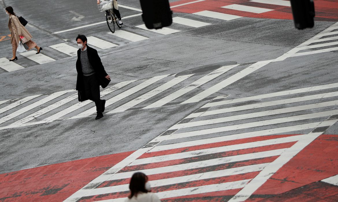 Os pedestres que usam máscaras protetoras, após um surto da doença de coronavírus, andam na travessia no distrito de compras e diversão de Shibuya, em Tóquio