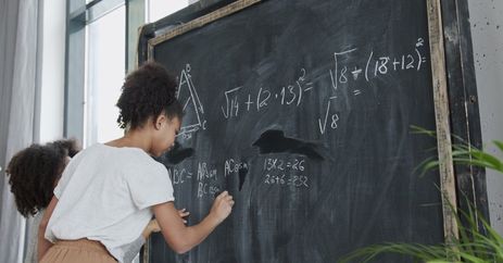 Crianças resolvem cálculos matemáticos na lousa