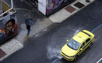 Rio de Janeiro - Pedestre caminha entre alagamentos na Rua da Relação, na Lapa, região central, durante temporal com forte chuva e vento  (Fernando Frazão/Agência Brasil)