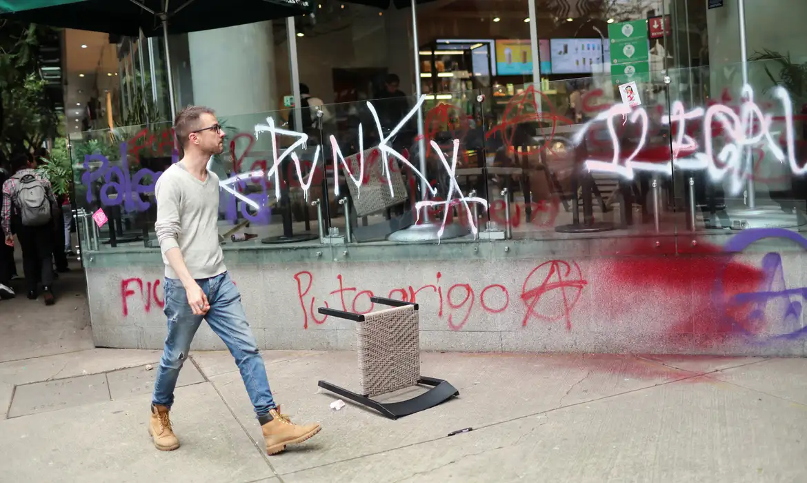 SENSITIVE MATERIAL. THIS IMAGE MAY OFFEND OR DISTURB A person passes by graffitis during a protest against gentrification in Condesa neighborhood, one of the most popular among digital nomads settled in Mexico City, Mexico July 4, 2025. REUTERS/Raquel Cunha