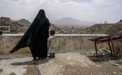 Uma mulher deslocada internamente e sua filha olham a cidade de Sanaa, no Iêmen, a partir do telhado do prédio onde estão abrigadas