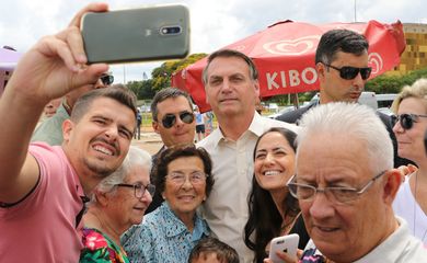 Presidente Jair Bolsonaro posa para foto com turistas na Praça dos Três Poderes em Brasília 