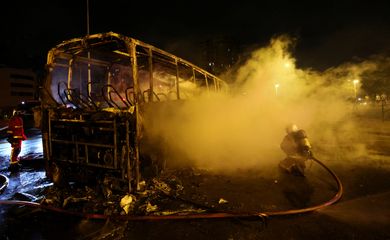 Um bombeiro usa uma mangueira de água em um ônibus queimado enquanto os distúrbios continuam após a morte de um adolescente de 17 anos morto por um policial francês durante uma parada de trânsito, em Nanterre, subúrbio de Paris, França, 1º de julho de 2023. REUTERS/Yves Herman