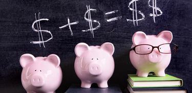 Três porquinhos de moeda em três pilhas de livros com cifrões em cima