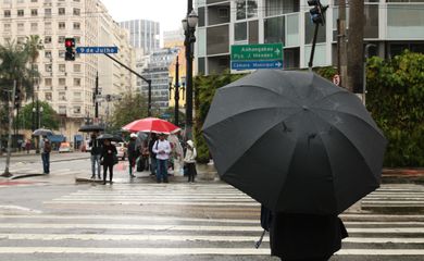 Pedestres se protegem da chuva no centro da capital paulista.