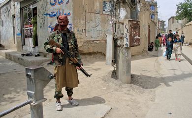 Taliban fighter stands guard at the site of an explosion in Kabul