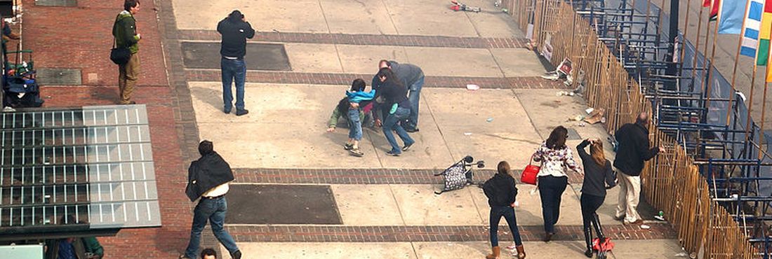 Vista do segundo andar de um edifício a meio quarteirão do local da primeira explosão em Boston mostra os civis auxiliando os feridos cerca de 10 segundos após a explosão