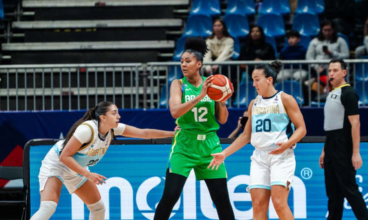 Santiago, 28/06/2025 - Jogadora da seleção brasileira, Damiris Dantas (camisa 12), a cestinha da partida, ataca a marcação de duas argentinas, durante partida contra o time da Argentina, na Americup feminina de basquete. Foto: FIBA/Divulgação